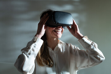 An young happy woman is using innovative technology vr glasses for play games and relax herself...