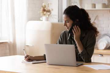 Confident young woman making phone call, taking notes, businesswoman consulting client or...