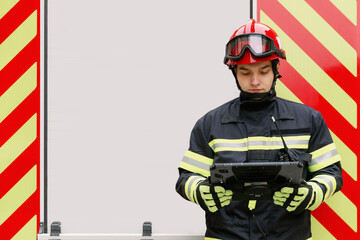 Fototapeta premium A man of strong physique in uniform and helmet stands by a rescue vehicle. A man rescuer stands at the white door of the car