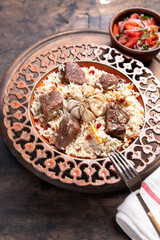 The concept of oriental cuisine. Traditional asian dish - pilaf from rice, vegetables and meat in a plate on a wooden table. background image. top view, copy space, flat lay