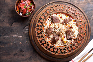 The concept of oriental cuisine. Traditional asian dish - pilaf from rice, vegetables and meat in a plate on a wooden table. background image. top view, copy space, flat lay