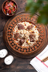 The concept of oriental cuisine. Traditional asian dish - pilaf from rice, vegetables and meat in a plate on a wooden table. background image. top view, copy space, flat lay