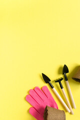 Flat lay of gardening supplies. Tools, peat pots and gloves on yellow background, space for text