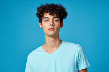 Fototapeta na wymiar guy with curly hair in blue t-shirt cropped view studio