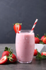Delicious strawberry drink in glass on grey table