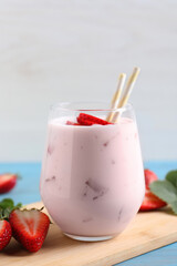 Delicious drink with strawberries on light blue wooden table