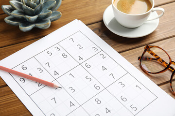 Fototapeta na wymiar Sudoku, pencil, eyeglasses and cup of coffee on wooden table
