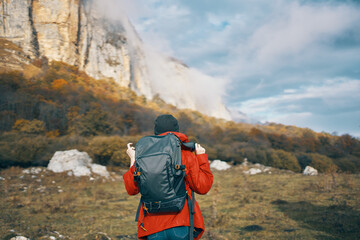 traveler with backpack in autumn in the mountains blue sky clouds high rocks landscape