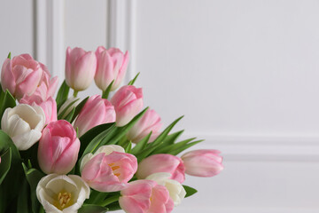 Beautiful bouquet of tulips against white wall, closeup. Space for text