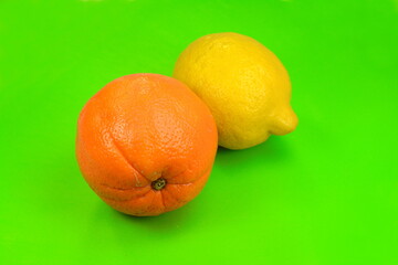 Fresh lemon and orange fruit on a green background.