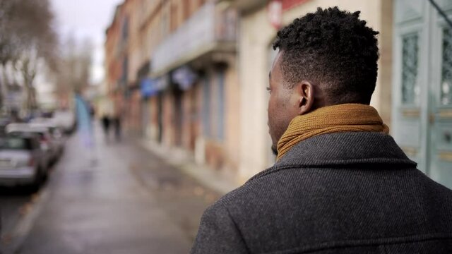 Young elegant black African man walking outside in city sidewalk