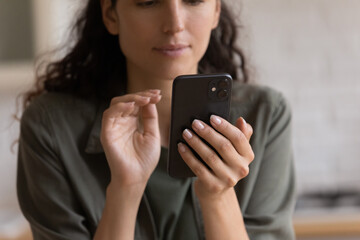 Close up cropped of focused woman looking at laptop screen, holding smartphone, typing, writing message in social network, scrolling, surfing internet, chatting or shopping online, browsing apps