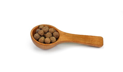 Allspice, pimento spice, Jamaican pepper pile in a wooden spoon isolated on white background