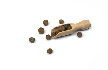Allspice, pimento spice, Jamaican pepper pile in a wooden spoon isolated on white background