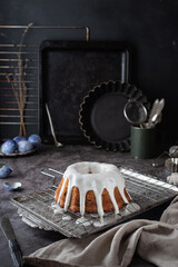 Dark Easter composition with a beautiful homemade Easter cake topped with white icing, against the background of old kitchen utensils. rustic still life in a dark style.