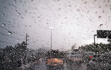Blur background driving car on metropolis road in trafic jam with raindrop ,rainy season