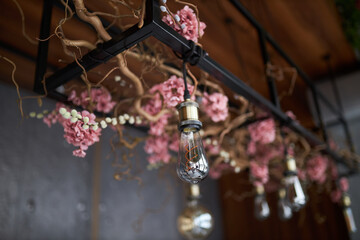 Home decor. Decorated electric lamps. Multi-colored light bulbs and flowers on the ceiling.