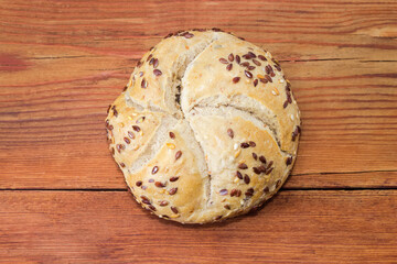 Round bun sprinkled with flax and sesame  on rustic table