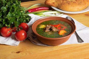 homemade meat soup with vegetables and parsley. Bowl with soup on a background of fresh vegetables and bread