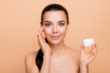 Close-up portrait of attractive naked girl using collagen cream smoothing effect lifting isolated over beige pastel color background