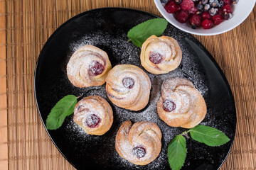 Sweet rolls decorated with mint leaves on dish, top view