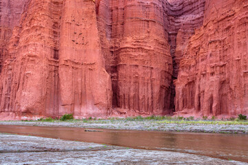Close up of an eroded natural rock wall with a small river in the foreground in the Quebrada de las Conchas, Argentina