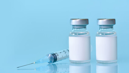 Two vials with a vaccine, a syringe on a blue background.The concept of medicine, healthcare and science.Coronavirus vaccine.Copy space for text.