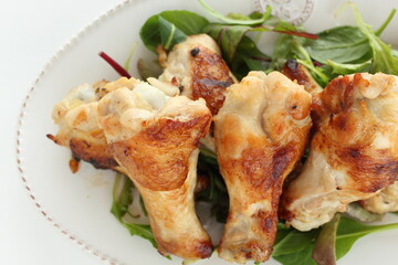 Homemade asian cuisine, barbecue grilled chicken drumsticks served with baby leaves and lemon