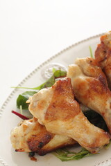 Homemade asian cuisine, barbecue grilled chicken drumsticks served with baby leaves and lemon