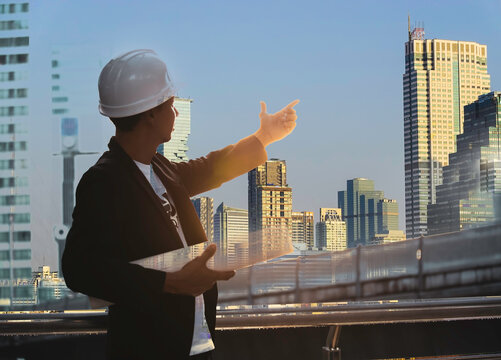 Double Exposure Of Attractive Engineer With Blue Print Working  At Work On Construction Site Which The Concept Of Engineering, Construction, City Life And Future