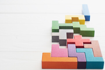 Different colorful shapes wooden blocks on white wooden background.