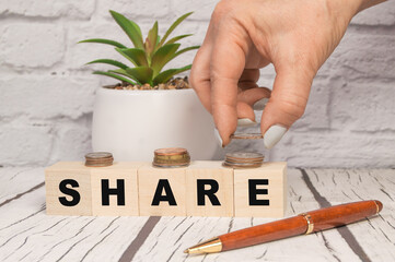 Share written on wooden dice, hand folding coins, the concept of profit and margin income