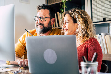 People at work at home with internet connection and computer laptop in couple - man and woman working together - modern man and woman online job activity in alternative house office