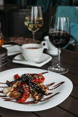 Caucasian salad with chicken eggplant pepper and glass of white wine. Warm salad with chicken and vegetables.