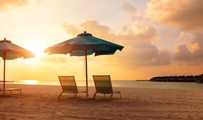 Sandy beach with deckchairs and umbrellas at sunset