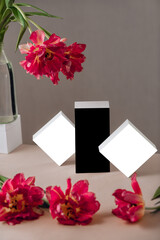 Gift or present box wrapped in white paper and tulip flowers on pink table. Copy space