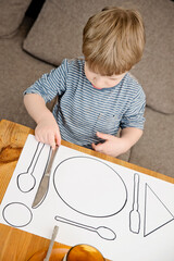 Fototapeta na wymiar Kid learning to Serve a Table. Task according to Montessori methodology.
