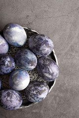 organic Easter eggs close-up, hand-painted with natural blueberries, lie in a clay cup on a stone table. Easter concept. flat lay