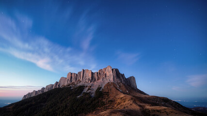 twilight panoramic mountain view, starry sky and clouds, city lights in the background