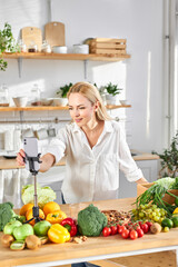 pretty cauacasian female in white shirt stand by table with many fresh natural products food, organic meal