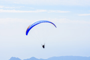 Paragliding in the sky. Paraglider tandem flying over the sea and mountains. Extreme sport