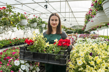 Woman farmer working in a garden center  and care her different flowers.