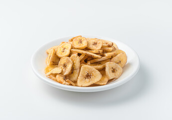 Dried bananas in a white plate on a light background.