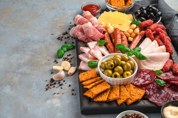 Charcuterie board with different types of sausage and cheese on a gray background with spices and garlic.