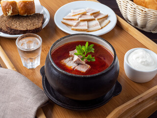 Borsch. Beet-cabbage soup with a meat slice. With lard, sour cream and vodka. Traditional serving of borscht. Russian, Ukrainian soup. Borscht in a cast-iron cauldron. Space for text. Rustic style. 