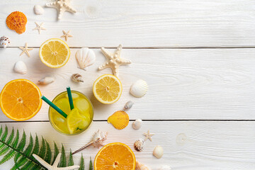 Summer background with fruit and a cooling drink. Oranges, lemons, juice and shells on a white background.