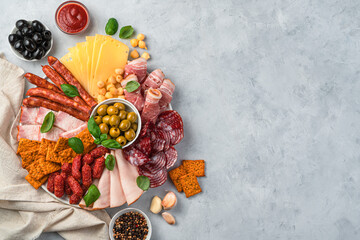 Meat and cheese delicacies with olives, sauce, spices and garlic on a light background.