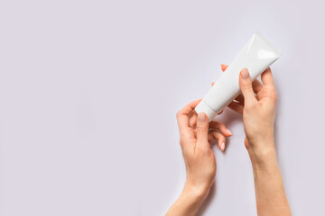 Beauty concept with woman hand and cream tube on lilac background