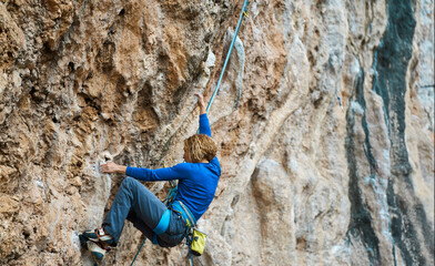 sports woman rock climber climbing on cliff, focused on difficult route and next move