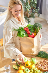 attractive female unpacking paper bag with fresh products